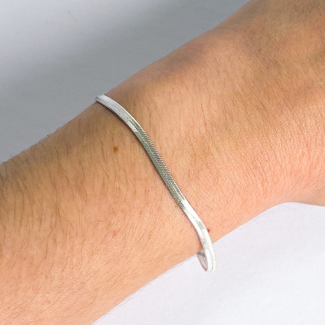 Silver bracelet on a wrist with a neutral background