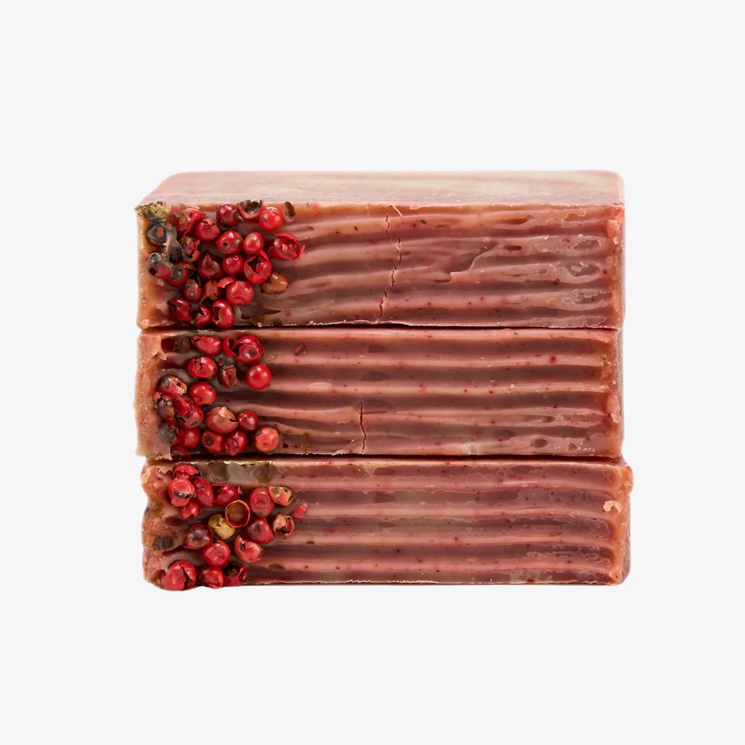 Bar of soap with a textured surface and red berries on a white background