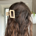 Close-up of a person's hair with a gold hair clip, indoor setting