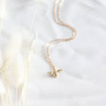 Gold bee necklace on a white background
