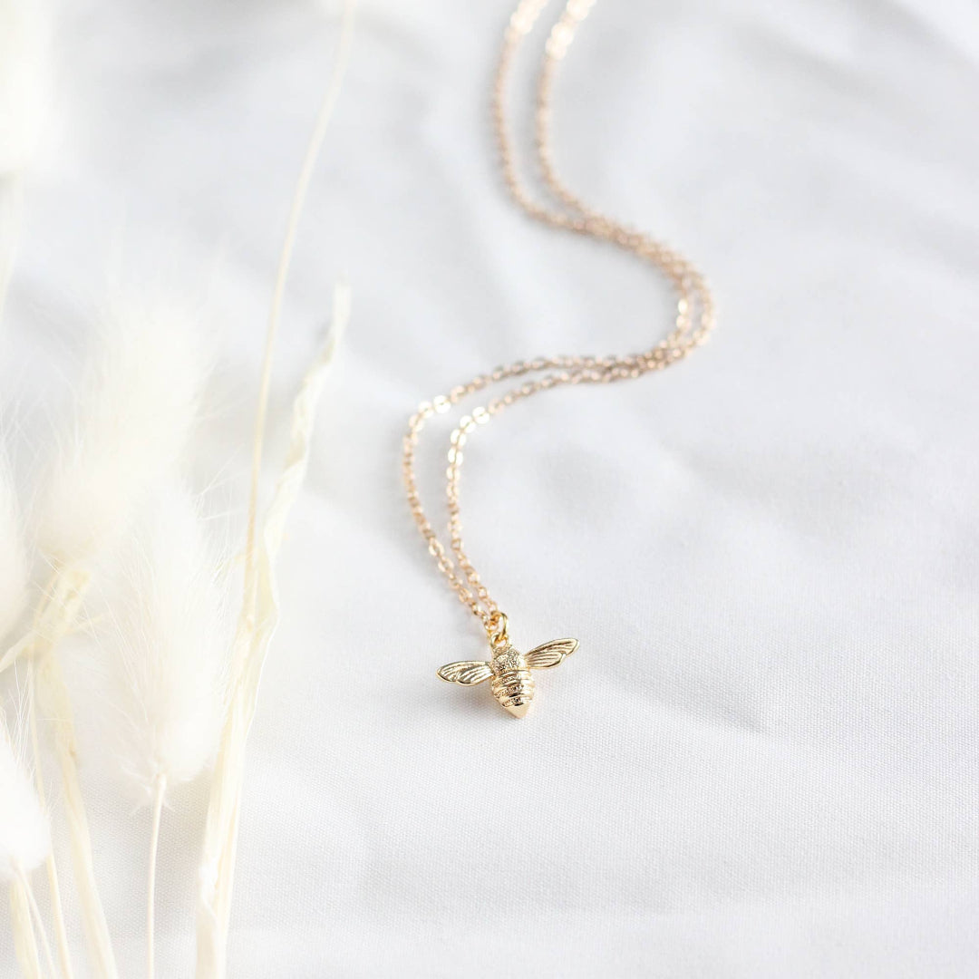 Gold bee necklace on a white background