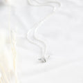 Silver necklace on a white fabric background