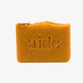 Bar of orange soap with 'aide' branding on a white background