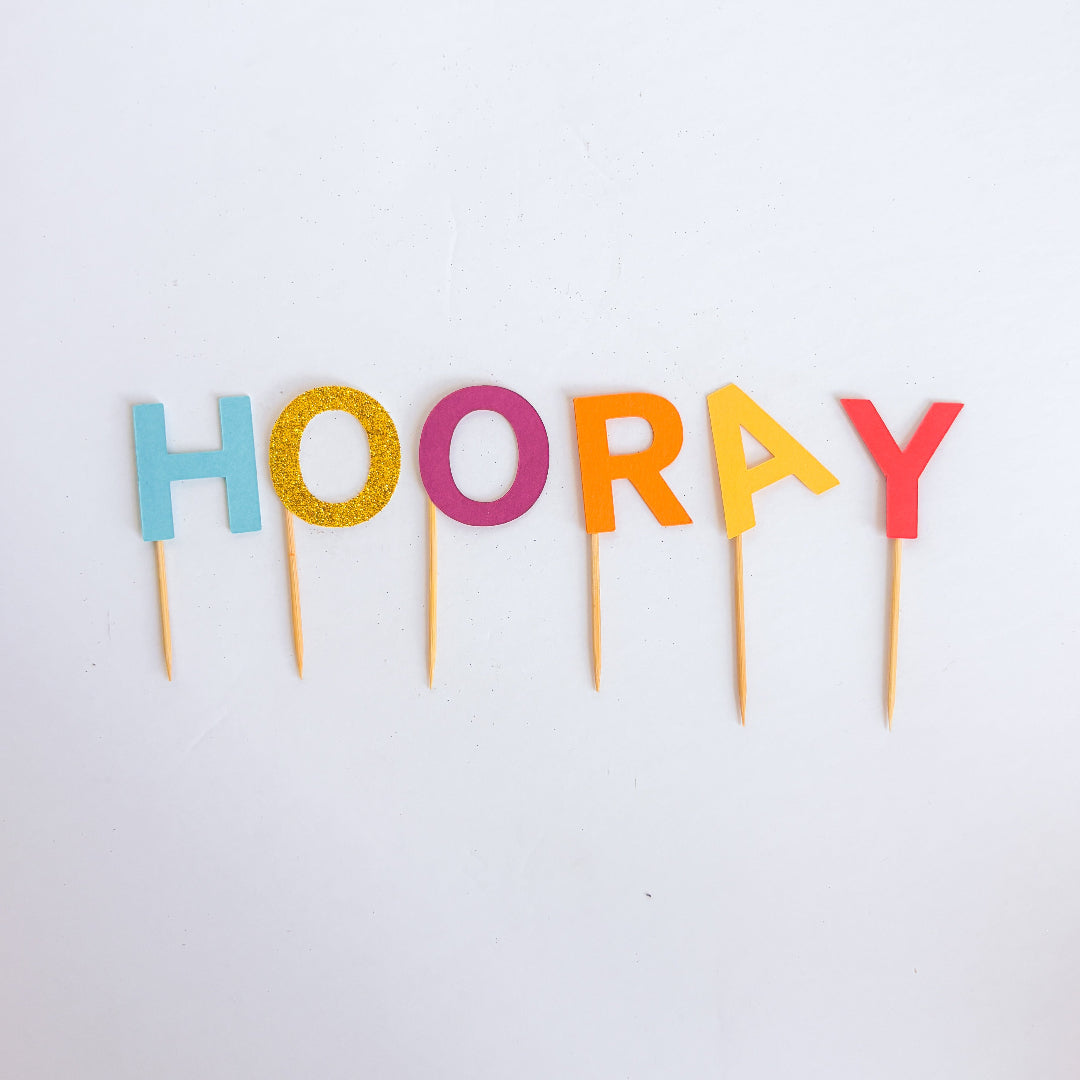 Colorful 'HOORAY' letter cake toppers on a white background