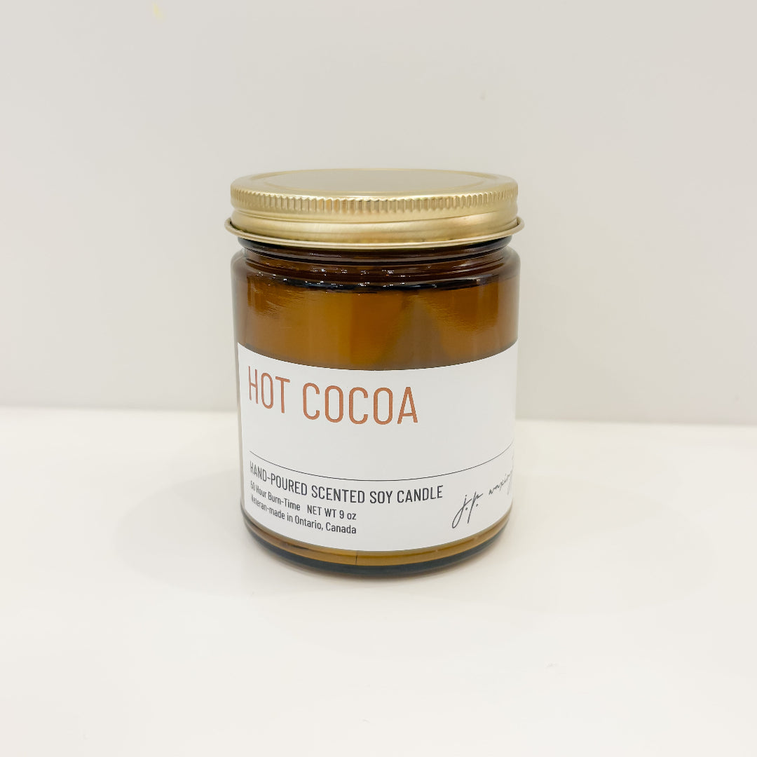Jar of 'Hot Cocoa' candle with a gold lid on a white background