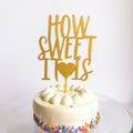 Small round cake with a 'How Sweet It Is' topper on a white background