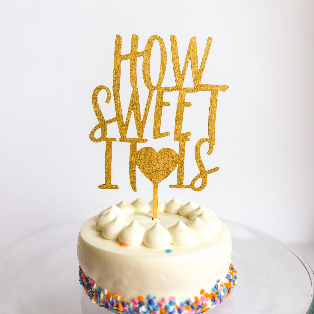 Small round cake with a 'How Sweet It Is' topper on a white background