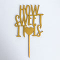 Gold cake topper with 'How Sweet It Is' text on a white background