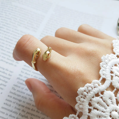 An 18K gold fill hug ring, featuring two hands gently wrapping around the finger, symbolizing love, friendship, and support. This open band ring is available in Ottawa, Ontario, Canada.
