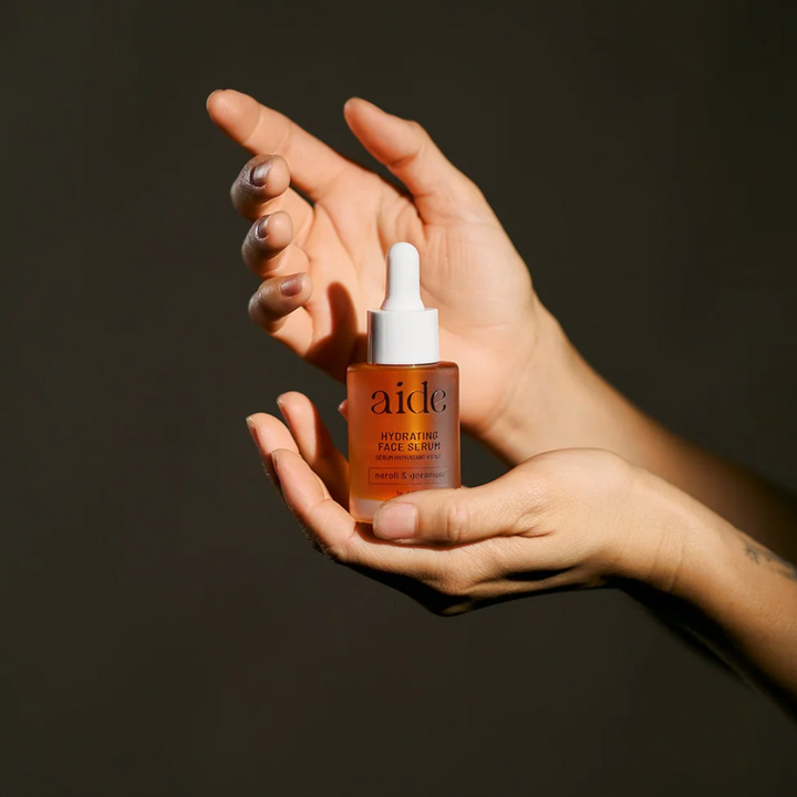 Aide Bodycare Hydrating Face Serum, featuring a small glass bottle with a dropper and a label with 'aide' logo, 'Hydrating Face Serum', and 'neroli & geranium' text, displayed on a light-colored surface. The serum is natural and available in Ottawa, Ontario, Canada.