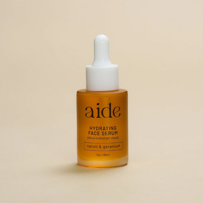 Aide Bodycare Hydrating Face Serum, featuring a small glass bottle with a dropper and a label with 'aide' logo, 'Hydrating Face Serum', and 'neroli & geranium' text, displayed on a light-colored surface. The serum is natural and available in Ottawa, Ontario, Canada.