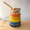 Colorful ceramic cup with a straw on a wooden surface