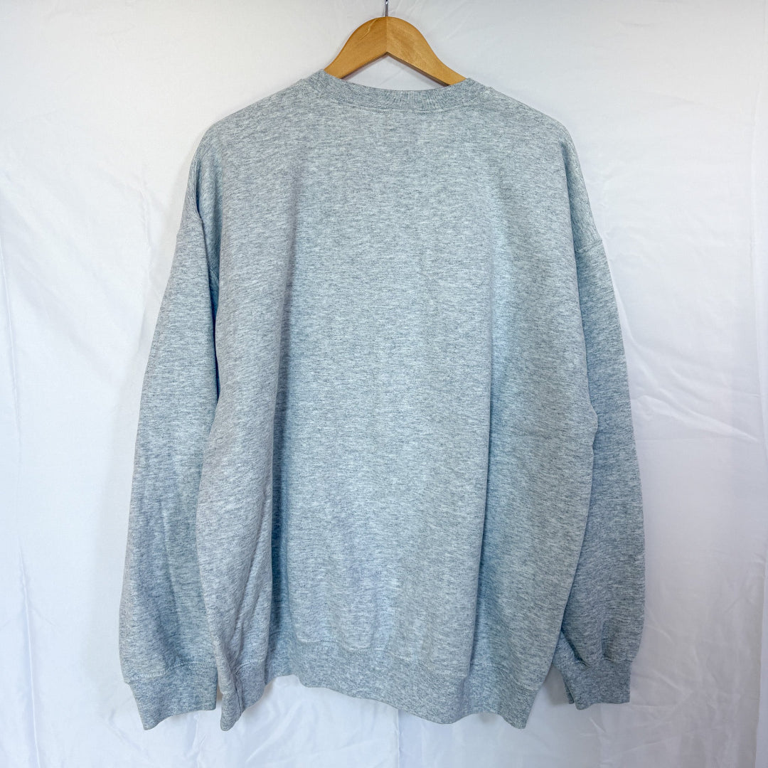 The back view of the same grey Gildan crewneck sweatshirt, hanging on a wooden hanger against a white background. The back is plain.