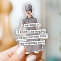 Hand holding a paper cutout with text and a person's silhouette, set against a blurred indoor background.