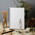 Notebook with a quote and illustration on a wooden surface with stationery items