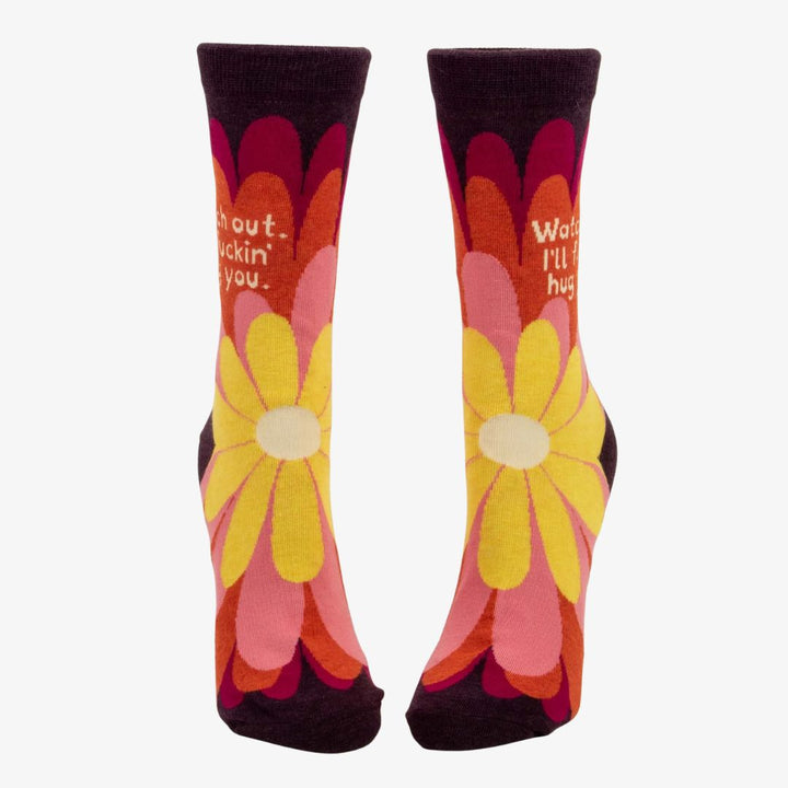 A pair of women's crew socks with a dark purple background and a vibrant, large floral pattern in shades of red, fuchsia, pink, and yellow. Text on one sock reads 