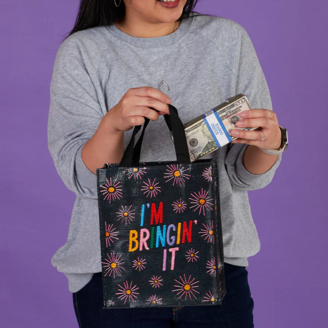 Woman holding a colorful tote bag with text and money against a purple background