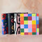 Four colorful agendas lined up on a marble surface. Each agenda has a unique design, including floral patterns, geometric shapes, and abstract designs. The word 