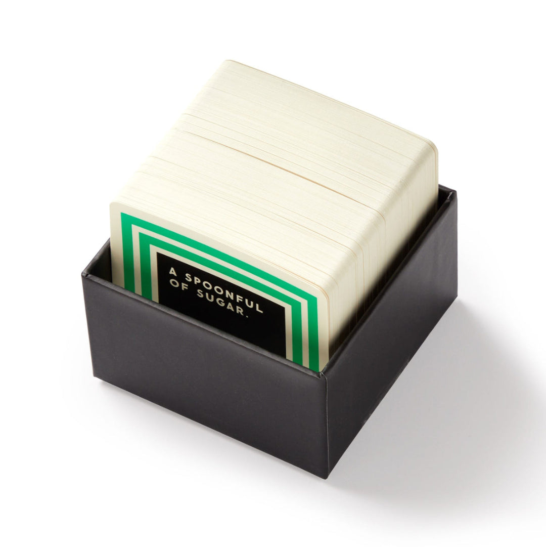 Stack of white sugar packets with a green label in a black holder on a white background