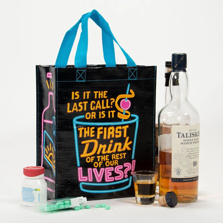 A black reusable tote bag with bright neon blue, pink, and yellow graphics. The front features a large cocktail glass with a cherry and straw, and text that reads 