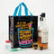 A black reusable tote bag with bright neon blue, pink, and yellow graphics. The front features a large cocktail glass with a cherry and straw, and text that reads 