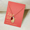 A gold necklace with a red garnet stone pendant. The pendant also has the word 