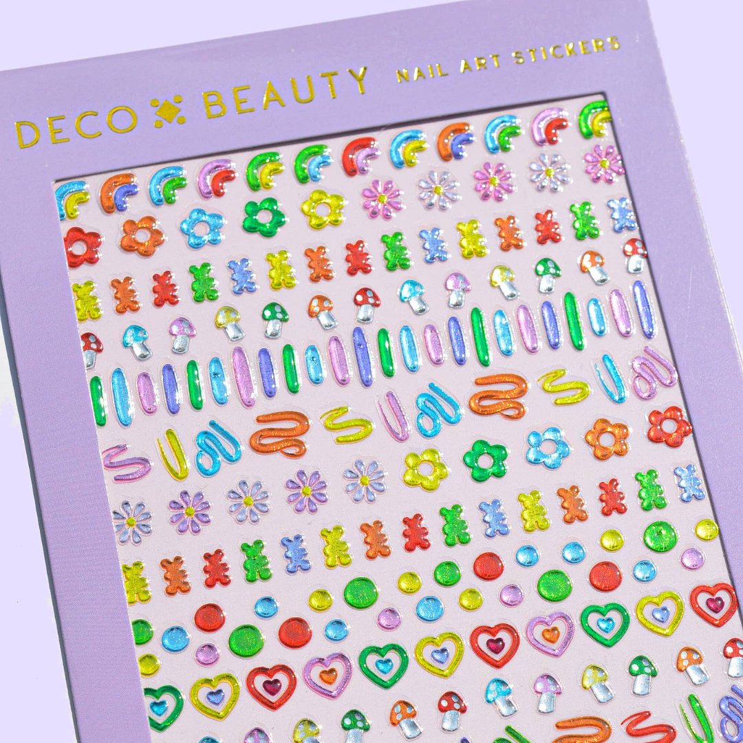 A sheet of colorful nail art stickers with various shapes like rainbows, mushrooms, flowers, and hearts. The sheet is purple and has the brand name "Deco Beauty" printed on it. There's a section titled "JELLY" and instructions on how to apply the stickers.