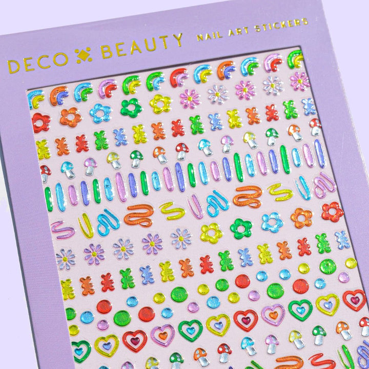 A sheet of colorful nail art stickers with various shapes like rainbows, mushrooms, flowers, and hearts. The sheet is purple and has the brand name 