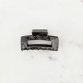 Black hair clip on a marble surface