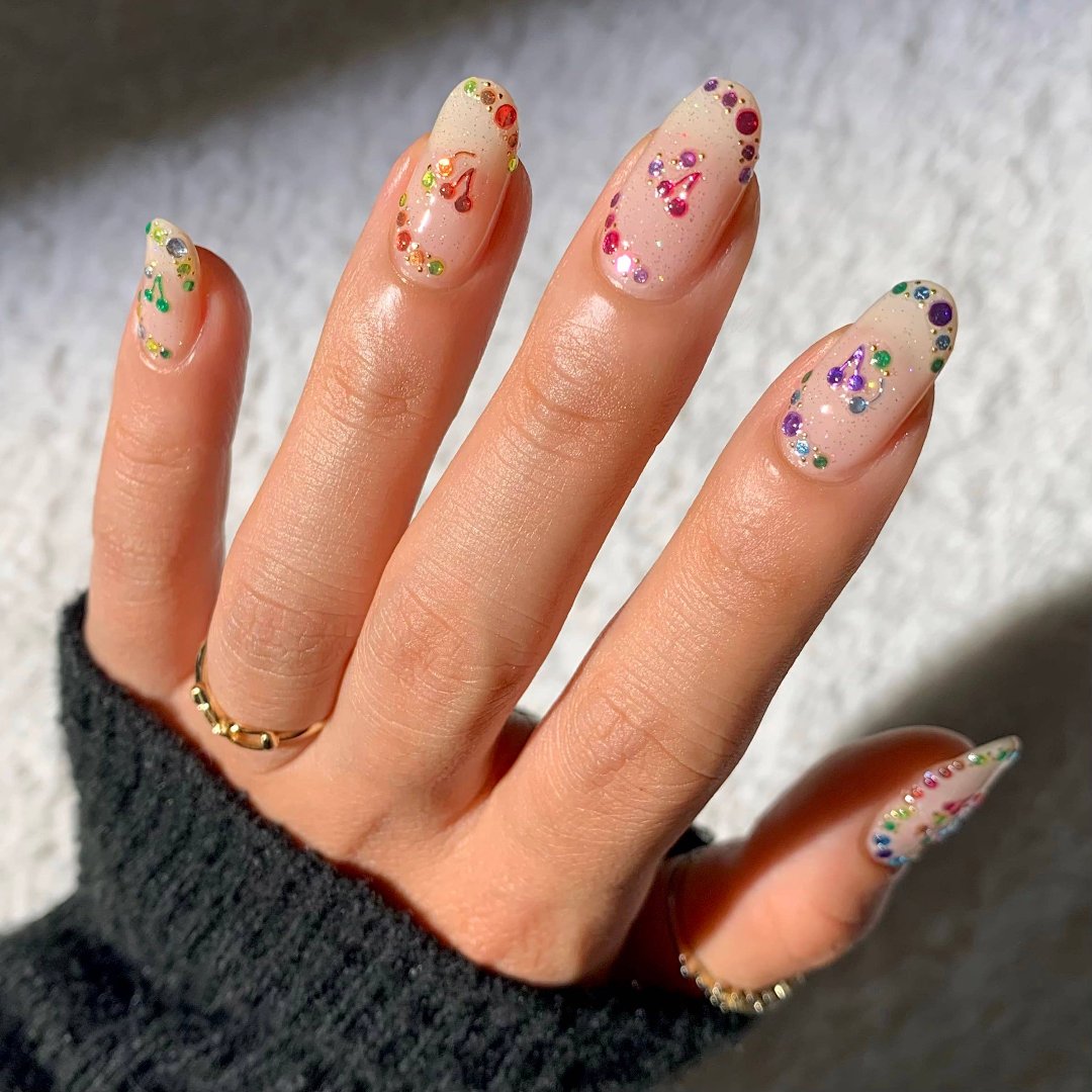 A sheet of colorful nail art stickers with various shapes like stars, hearts, flowers, and geometric designs. The sheet is holographic and has the brand name "Deco Beauty" printed on it. There's a section titled "JEWELS" and instructions on how to apply the stickers.