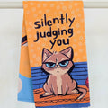 Towel with a cat illustration and text 'silently judging you' on an orange background