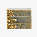 Three bars of marbled soap with gold leaf on a white background