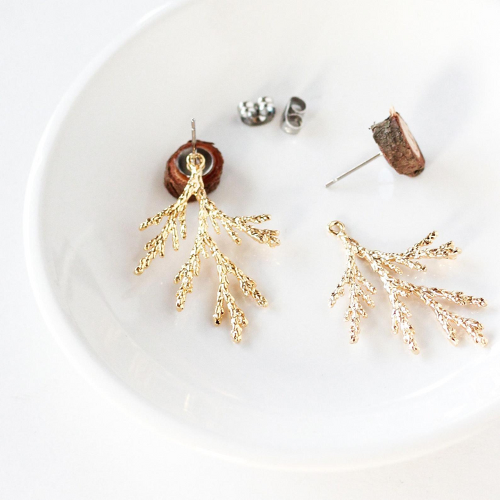 A pair of gold-colored branch earrings with detachable ear jackets. The earrings are displayed on a white plate with the ear jackets and posts visible.
