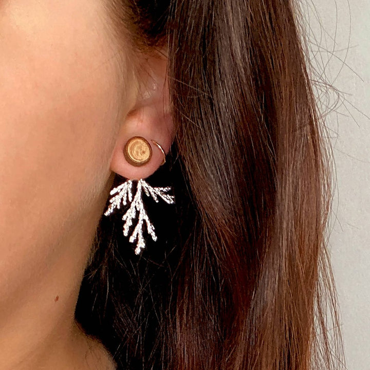 A pair of silver-colored branch earrings with detachable ear jackets. 