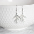 Silver branch-like earring on a white background