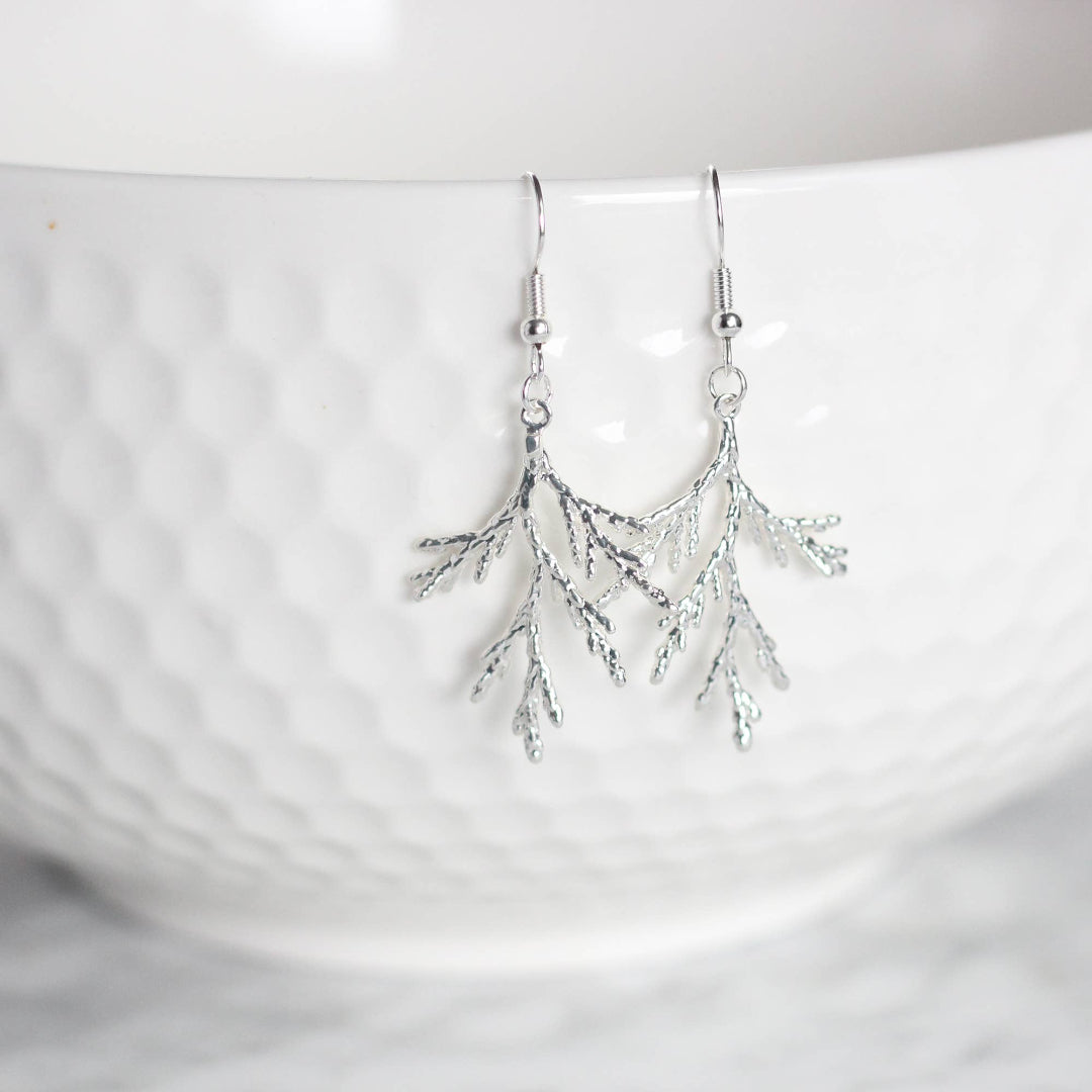 Silver branch-like earring on a white background