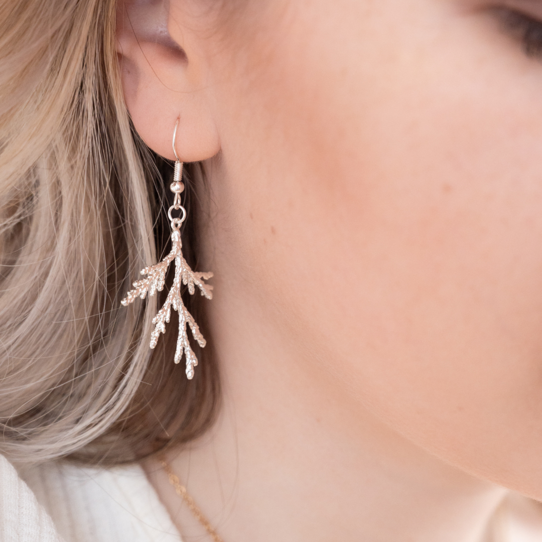 Close-up of a person wearing a delicate silver earring with a blurred background