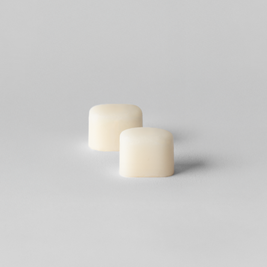 Two small white cylindrical objects on a light gray background