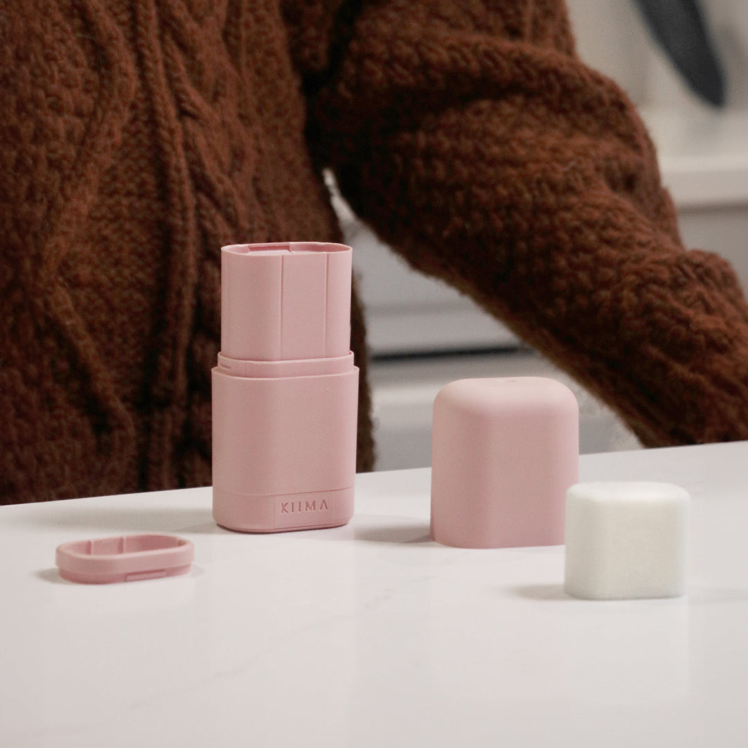 Pink cylindrical container with a person wearing a brown sweater in the background
