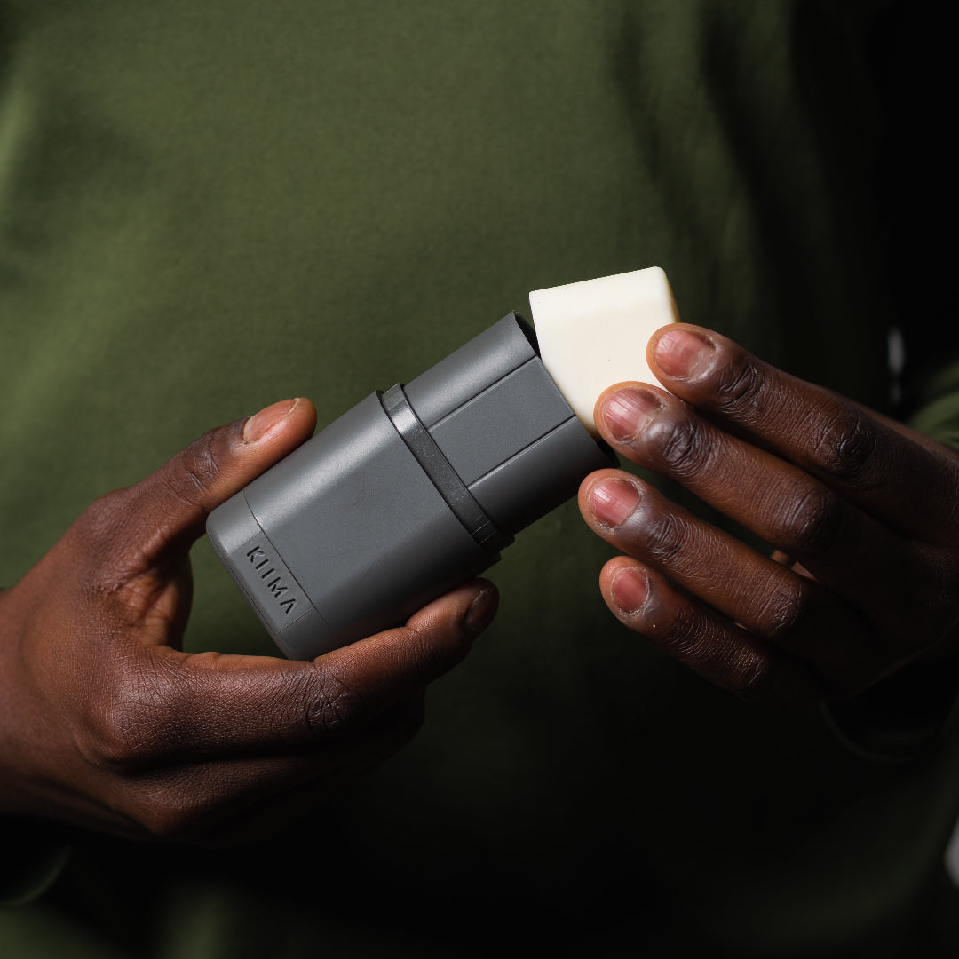 Person holding a gray electronic device with a white component against a dark background