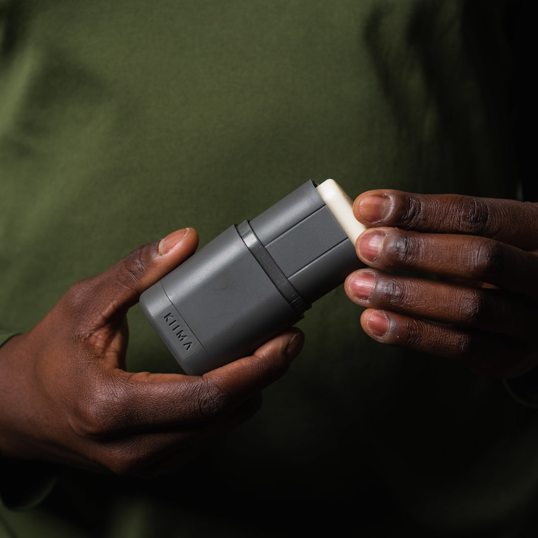 Person holding a gray device with a white component against a dark background