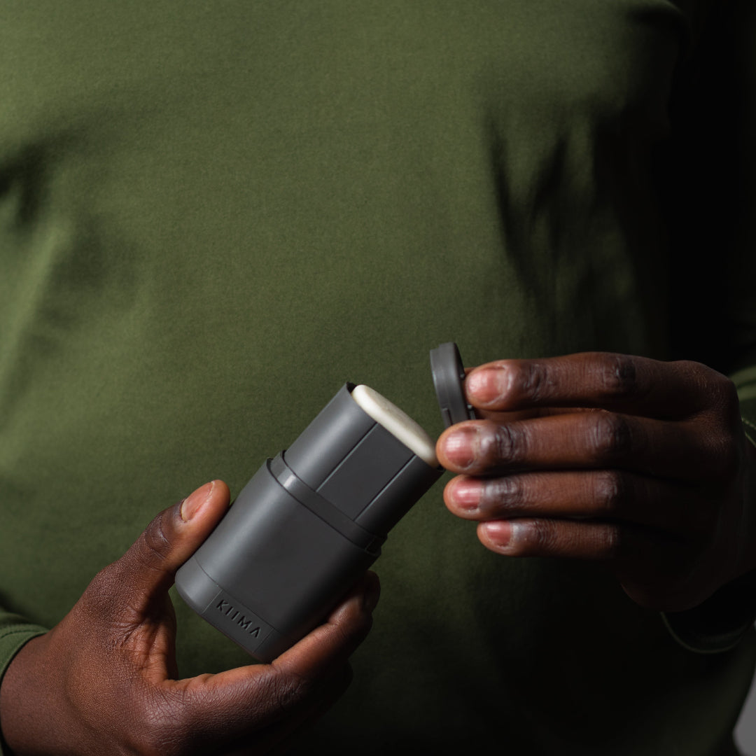Person holding a small electronic device against a green shirt background