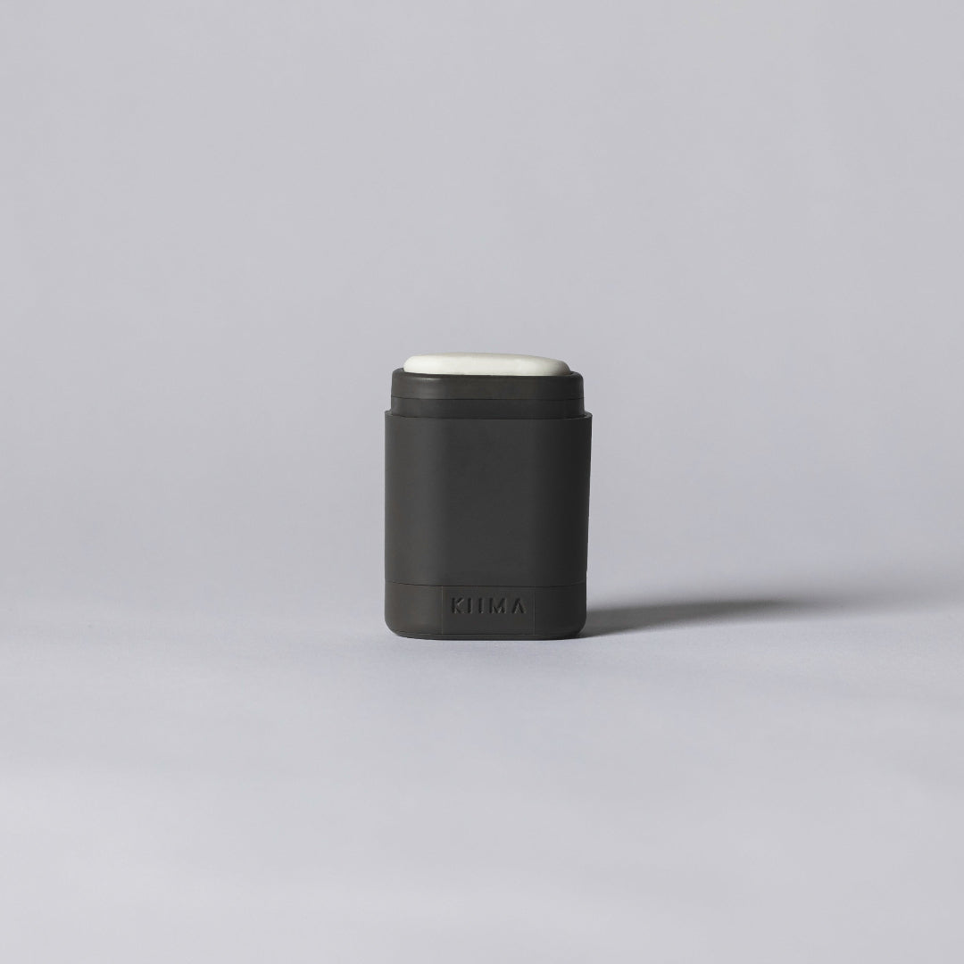 Black cylindrical container with a white cap on a gray background