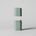 Two green containers with white lids on a light gray background