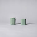 Two green cylindrical containers on a light gray background