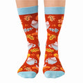 A pair of red socks with a fall-themed design. The socks feature pumpkins, cinnamon sticks, whipped cream, and the phrase "LET'S SPICE THINGS UP."