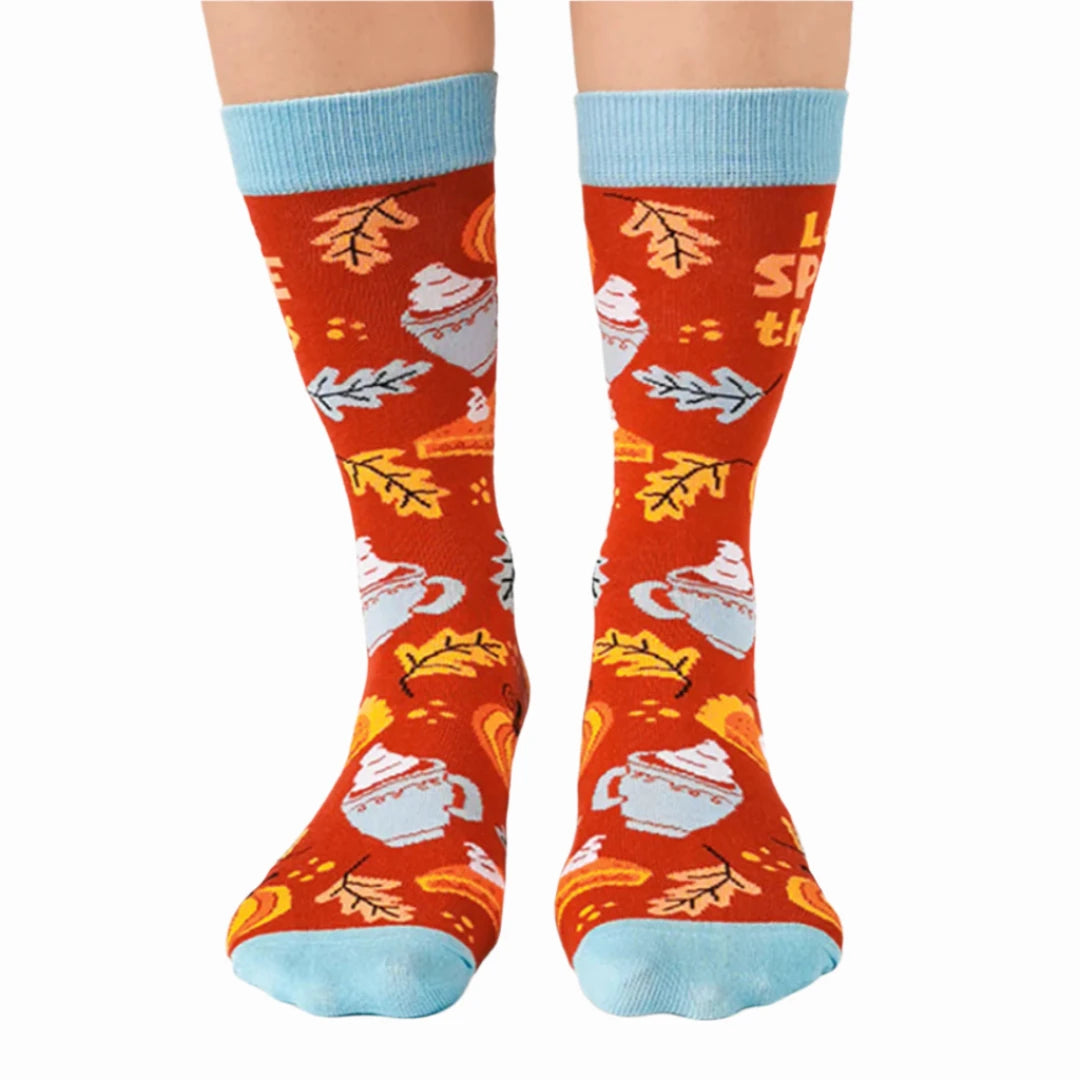 A pair of red socks with a fall-themed design. The socks feature pumpkins, cinnamon sticks, whipped cream, and the phrase "LET'S SPICE THINGS UP."