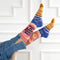 A pair of pink socks with a beach-themed design. The socks feature a beach scene, waves, and the text 