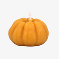 A small, pumpkin-shaped beeswax candle. The candle is orange with detailed ridges and a wick in the center.