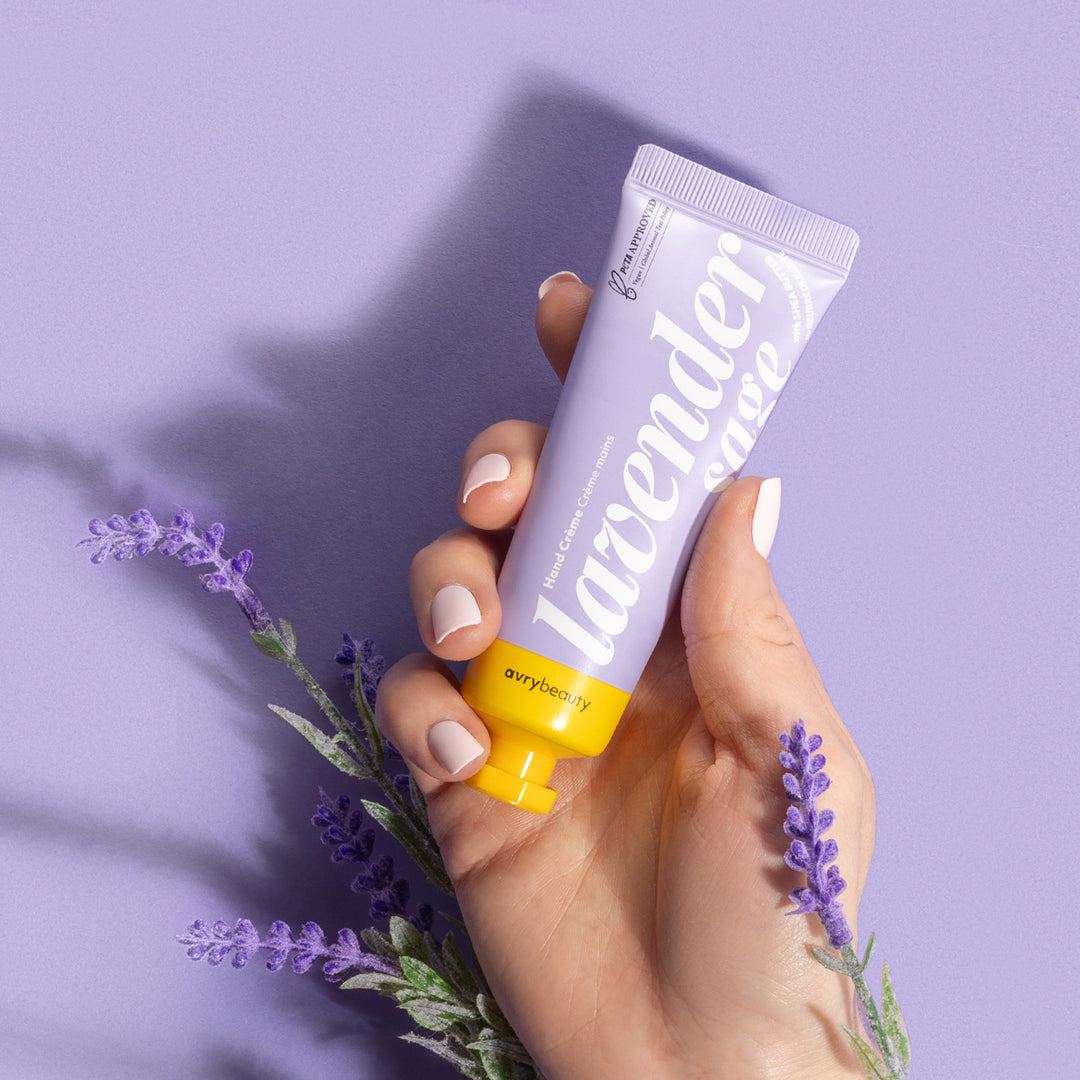 Hand holding a tube of lavender cream with lavender flowers on a purple background